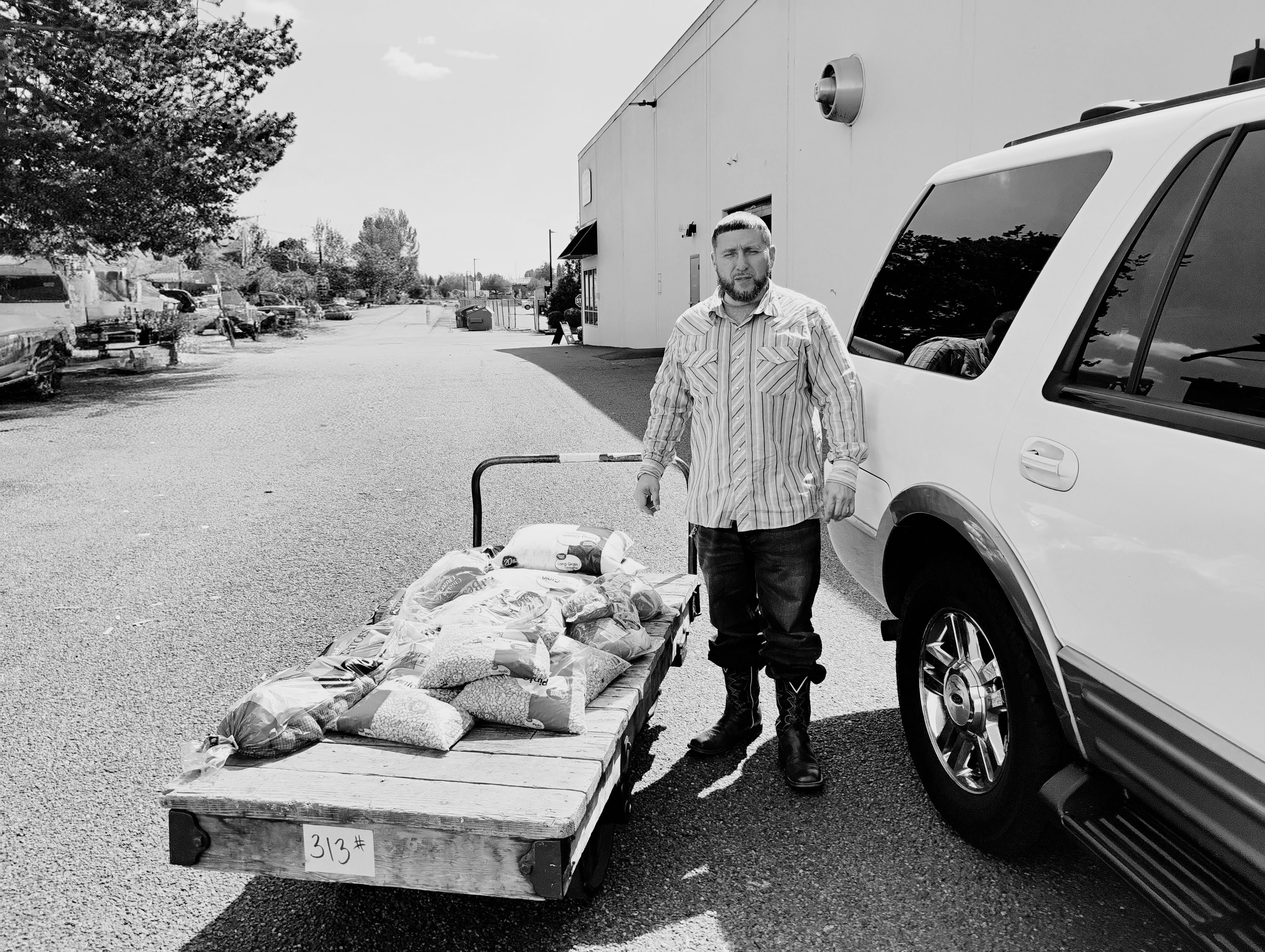 Richard standing with 313 lbs of food on pallet next to truck